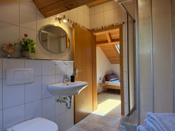 Badezimmer Helles Badezimmer mit Waschbecken, Spiegel und offener Tür zu einem Schlafzimmer.