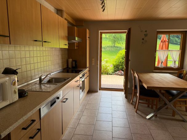 Große Küche Helle Küche mit Holzschränken, Essbereich und Fenstern zum Garten.
