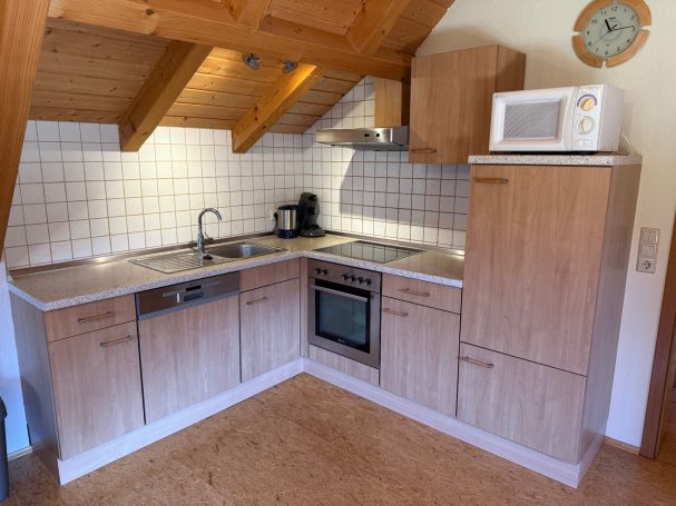 Offene Küche Moderne Kücheneinheit mit Holzregalen, Herd, Mikrowelle und Spüle.