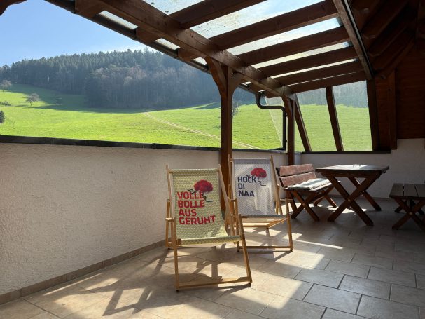 Großer Balkon Sonniger Balkon mit Liegestühlen und Blick auf eine grüne Landschaft.