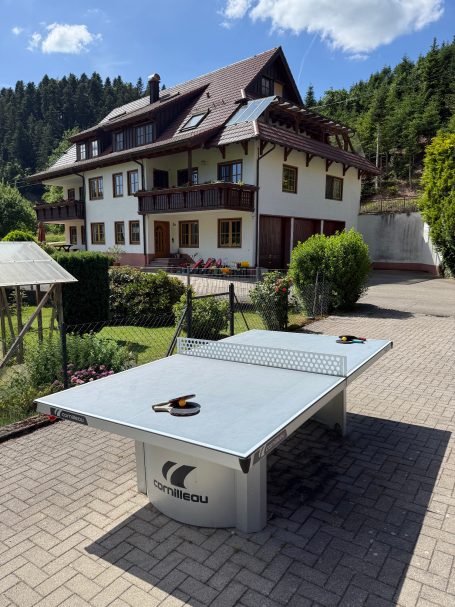 Tischtennisplatte Tischtennisplatte vor einem großen, schönen Haus mit Garten im Hintergrund.