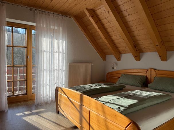 Großes Schlafzimmer Helle Schlafzimmer mit Holzdecke, zwei Betten und Fenster mit Vorhängen.