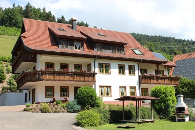 Das Ferienhaus Einfamilienhaus mit Balkon und Garten, umgeben von Bäumen und Hügeln.