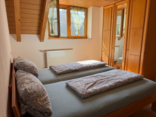 Schlafzimmer 1 Klassisches Schlafzimmer mit zwei Einzelbetten und großen Fenstern.