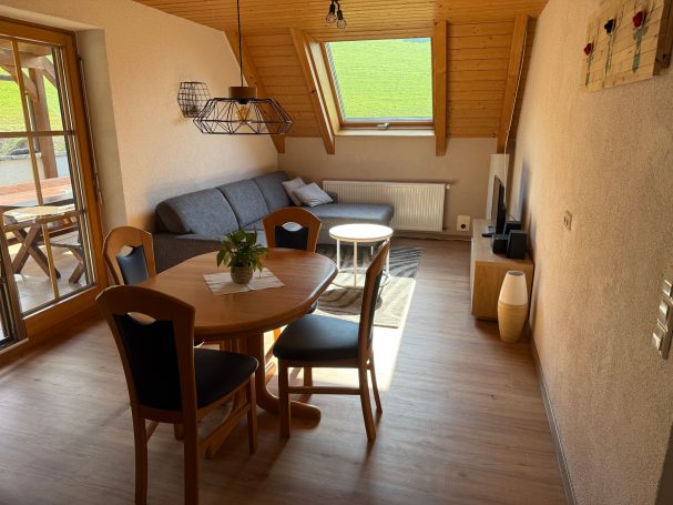 Wohn-/Esszimmer Heller Wohnraum mit Tisch, Stühlen, Sofa und Fenster im Dachbereich.