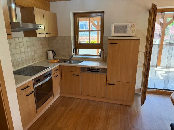 Küche Kleine moderne Küche mit Holzschränken, Herd, Mikrowelle und Fenster nach draußen.